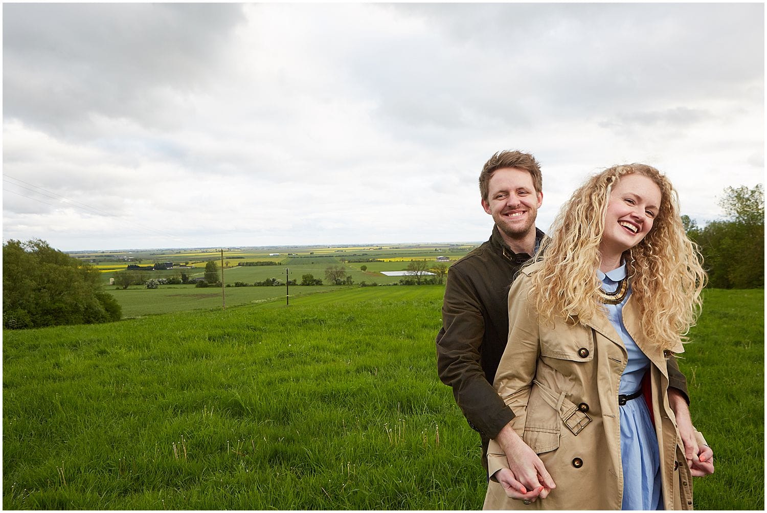 A couple smiling in the countryside during an engagement photoshoot