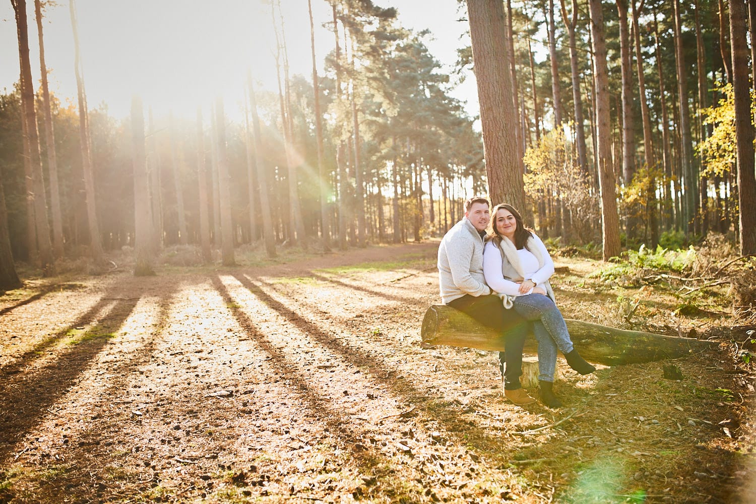 A couple sit together on a fallen log in Woodhall Spa Woodland Lincolnshire