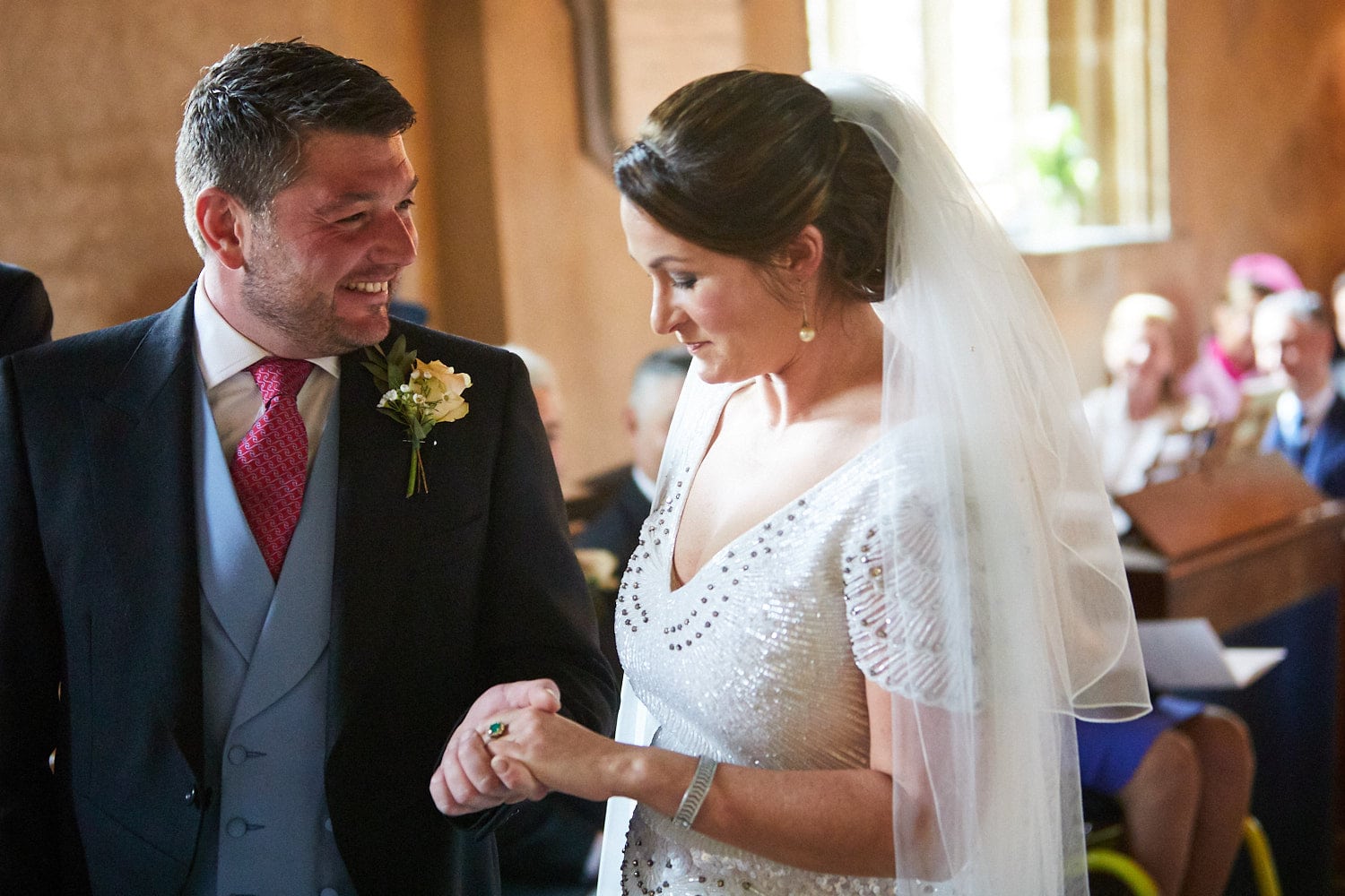 A groom smiles as he looks at his wife lovingly after they exchanged rings on their wedding day