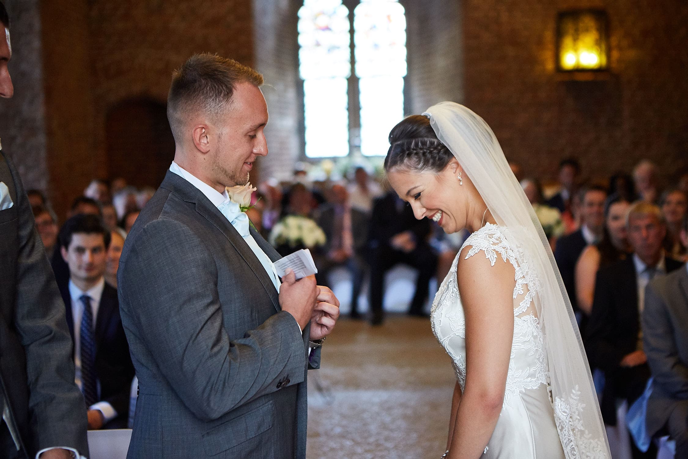 A groom pulls out his vows whilst his bride laughs