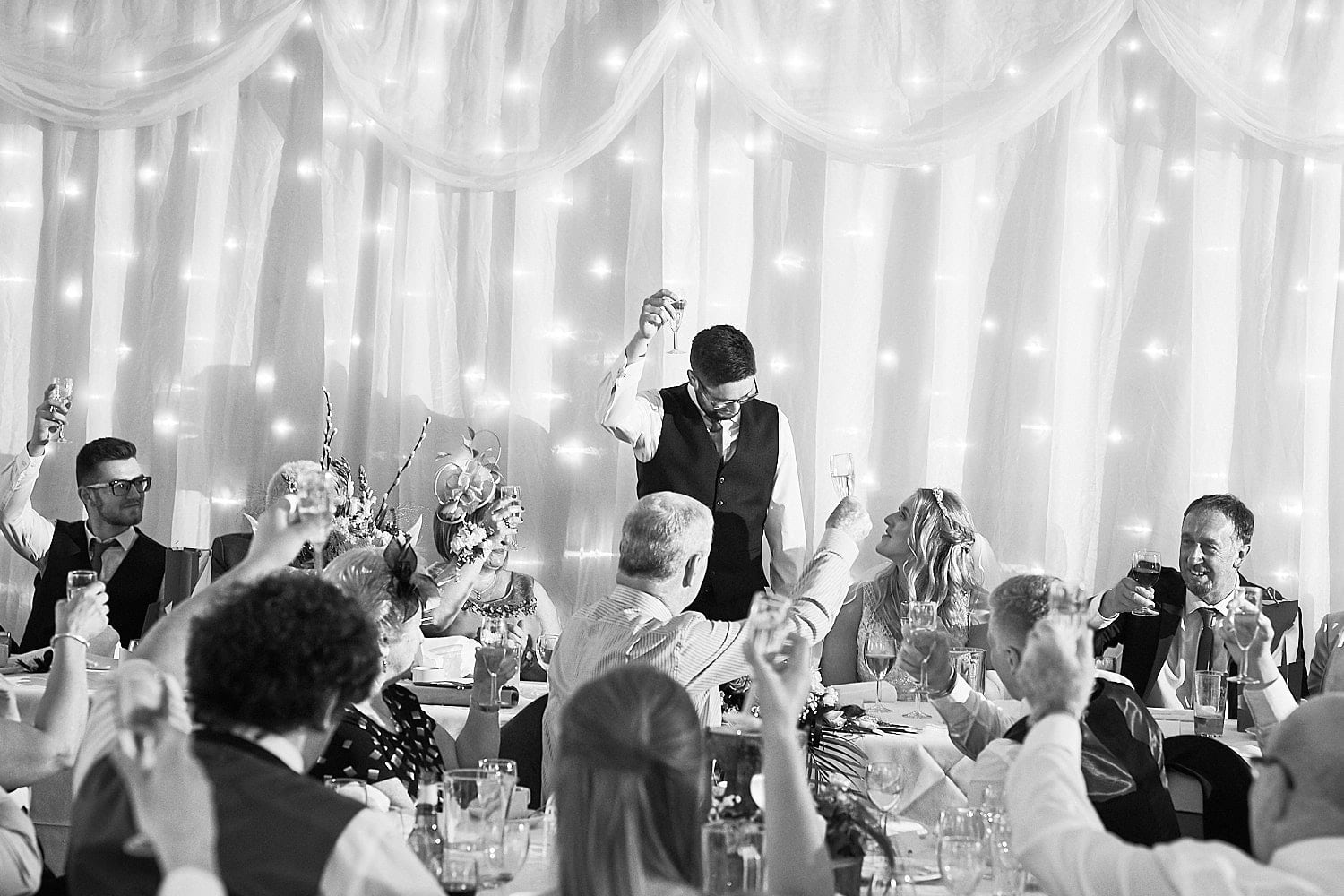 A groom toasts the room during his speech
