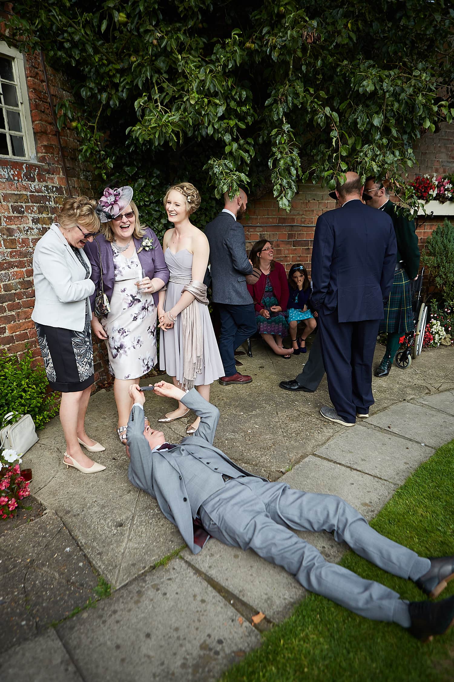 A man laid on the floor shooting a photograph of 3 women. at a Lincolnshire Wedding
