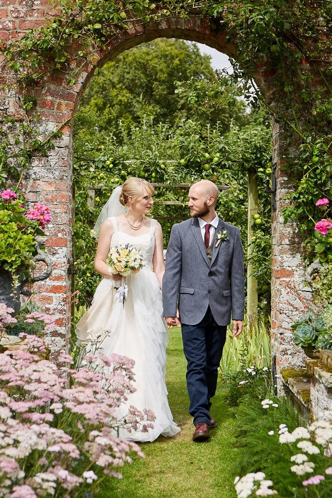A couple walk through the gardens of Gunby Hall on their wedding day