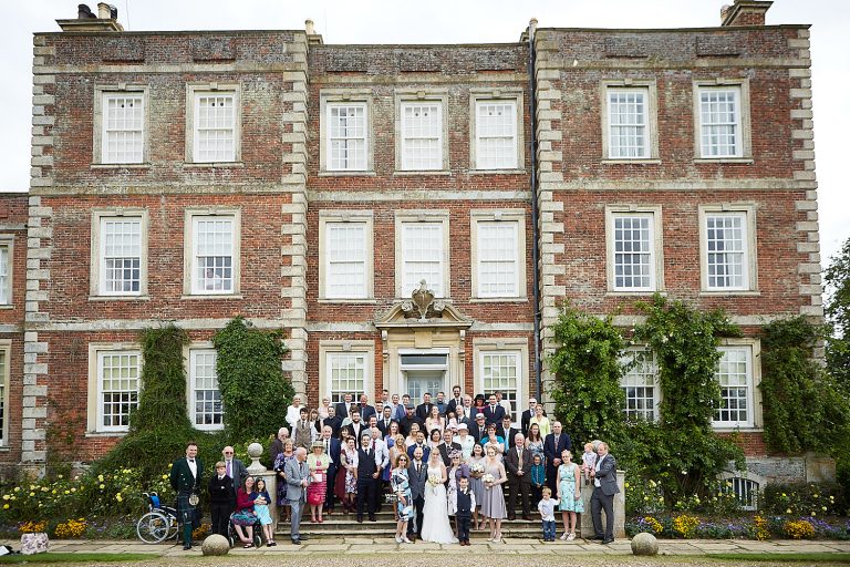 A wedding party stand in front of the main house at Gunby Hall National Trust Wedding venue for a group shot