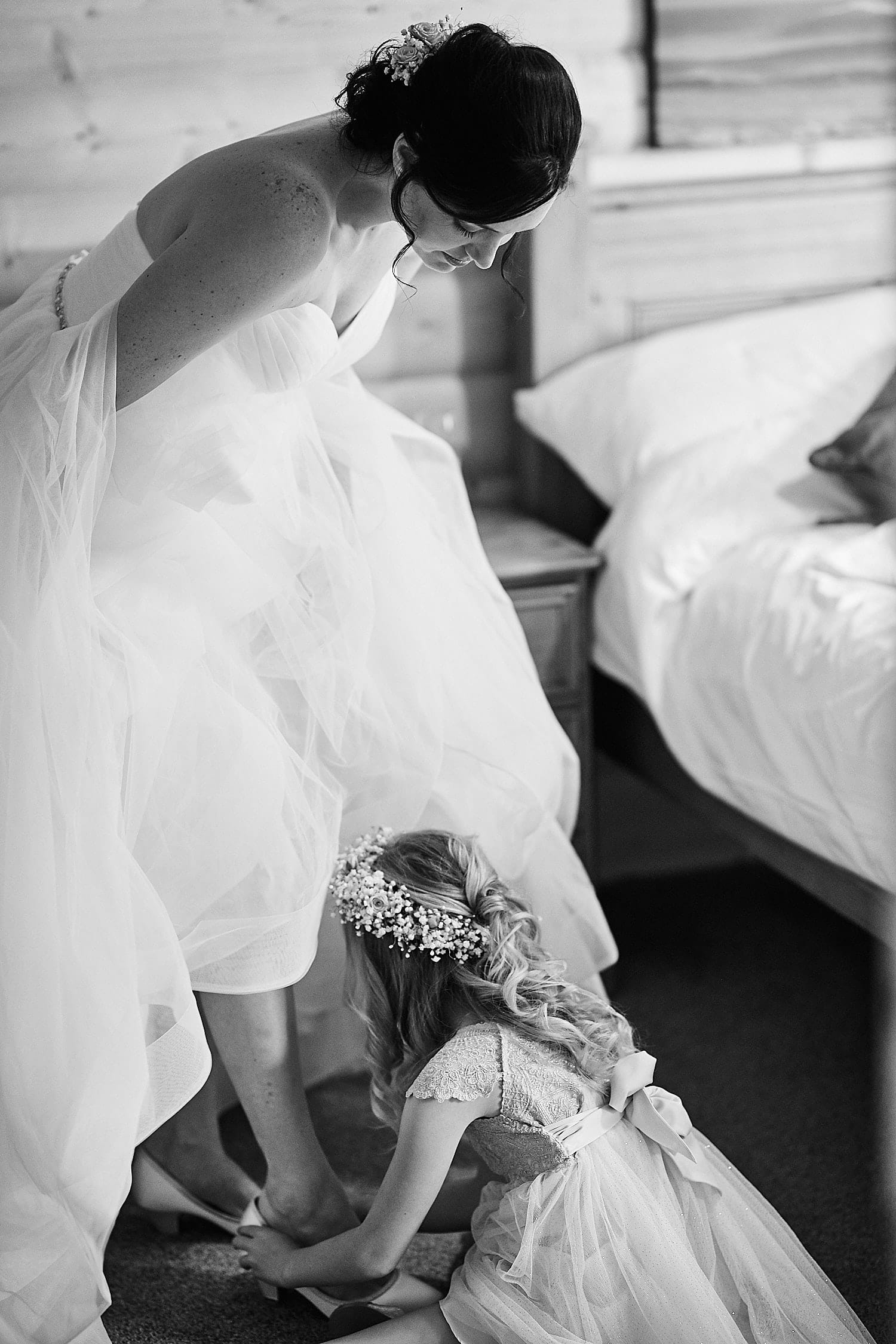 A girl helps her mother put on her wedding shoes
