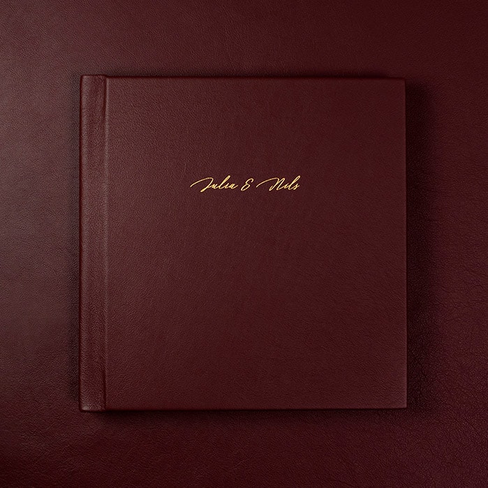 A red leather wedding album against a red leather background