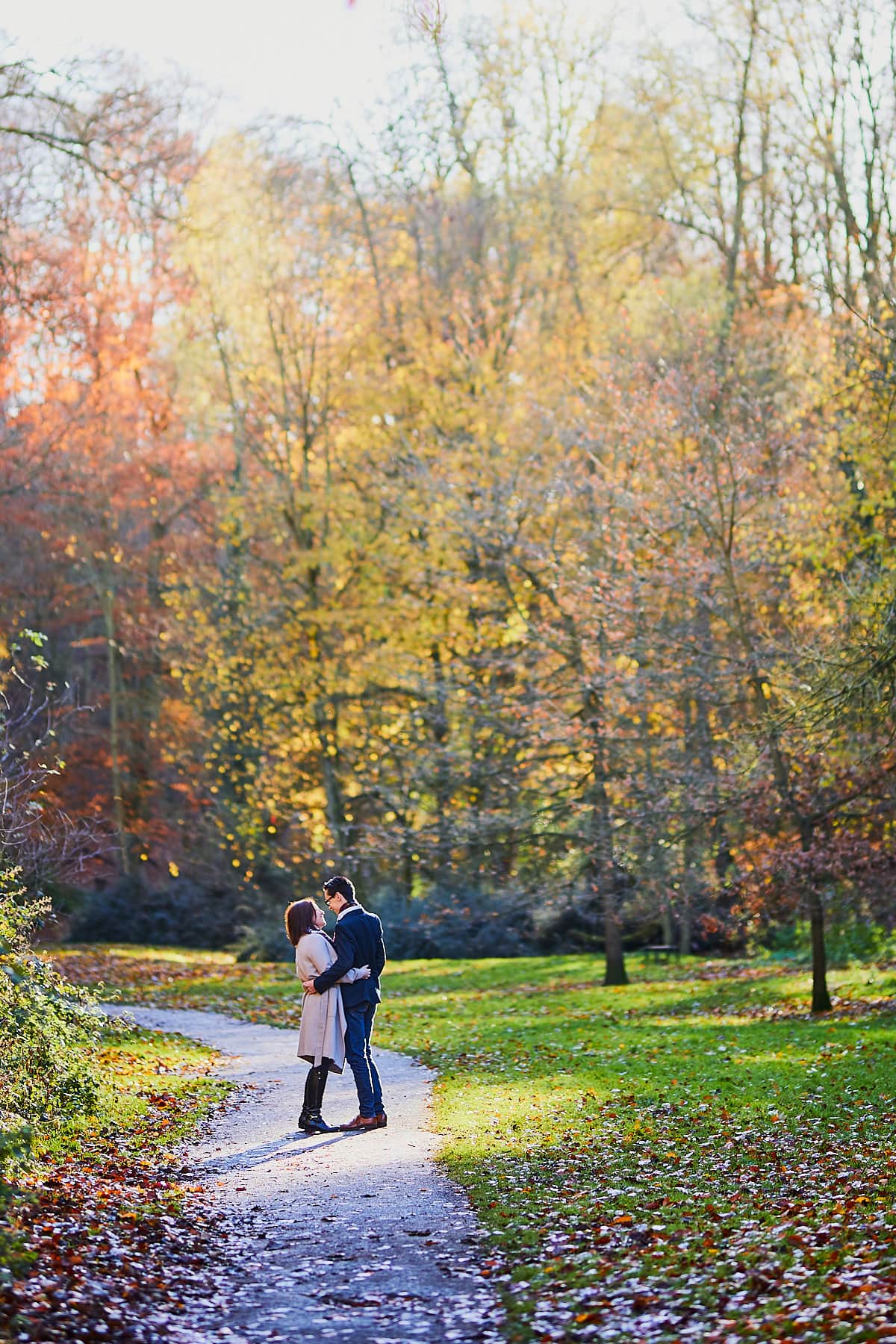 A winter woodland photoshoot sees a couple embrace in front of the colour of changing leaves