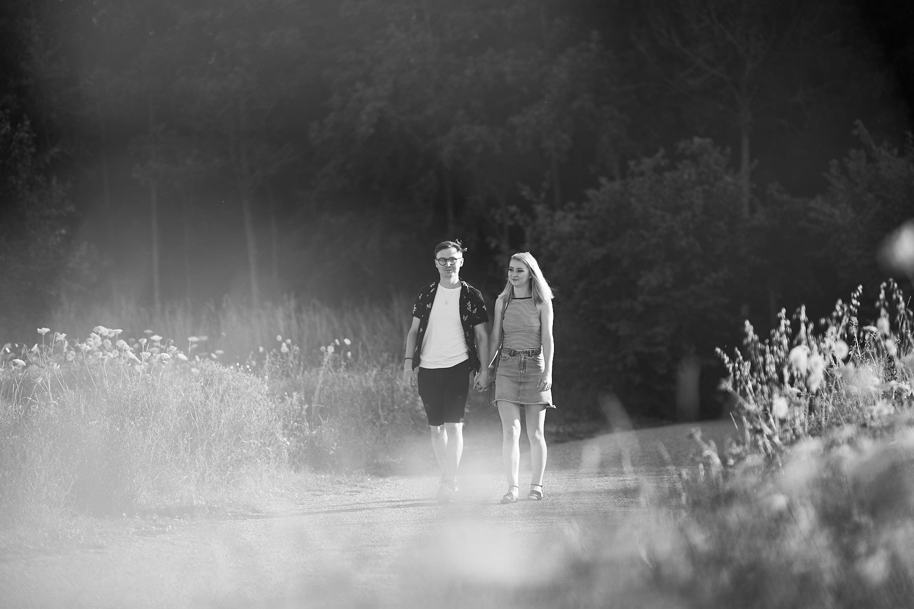 A couple walk together during the summer in woodland