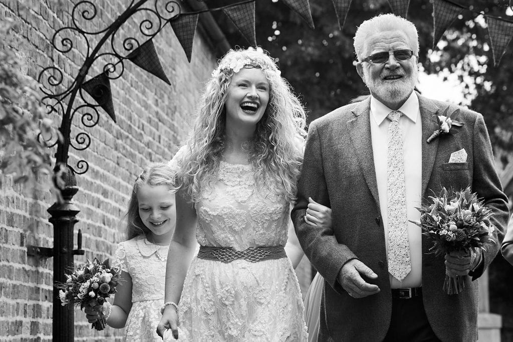 A bride and her father walk to Raithby Church on her wedding day.