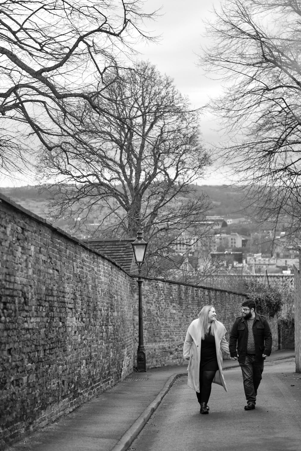 A black and white photo of a couple walking around the Bailgate area of Lincoln holding hands